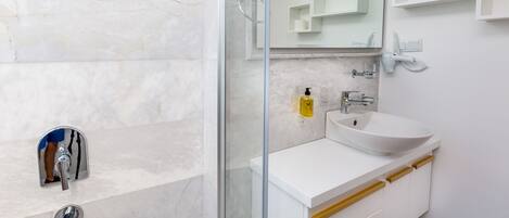 A modern bathroom with a glass-enclosed shower, a white sink, and a mirror above the sink.