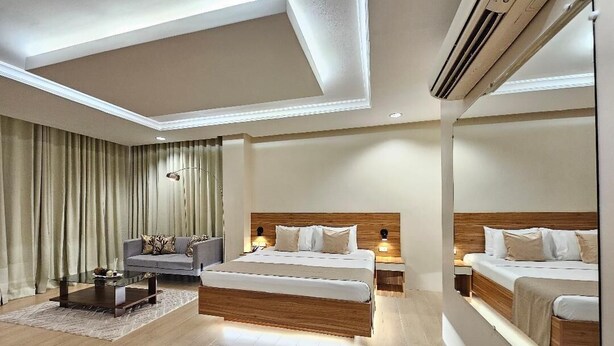 Een moderne hotelkamer met een groot bed, een bank, een salontafel en een spiegel.