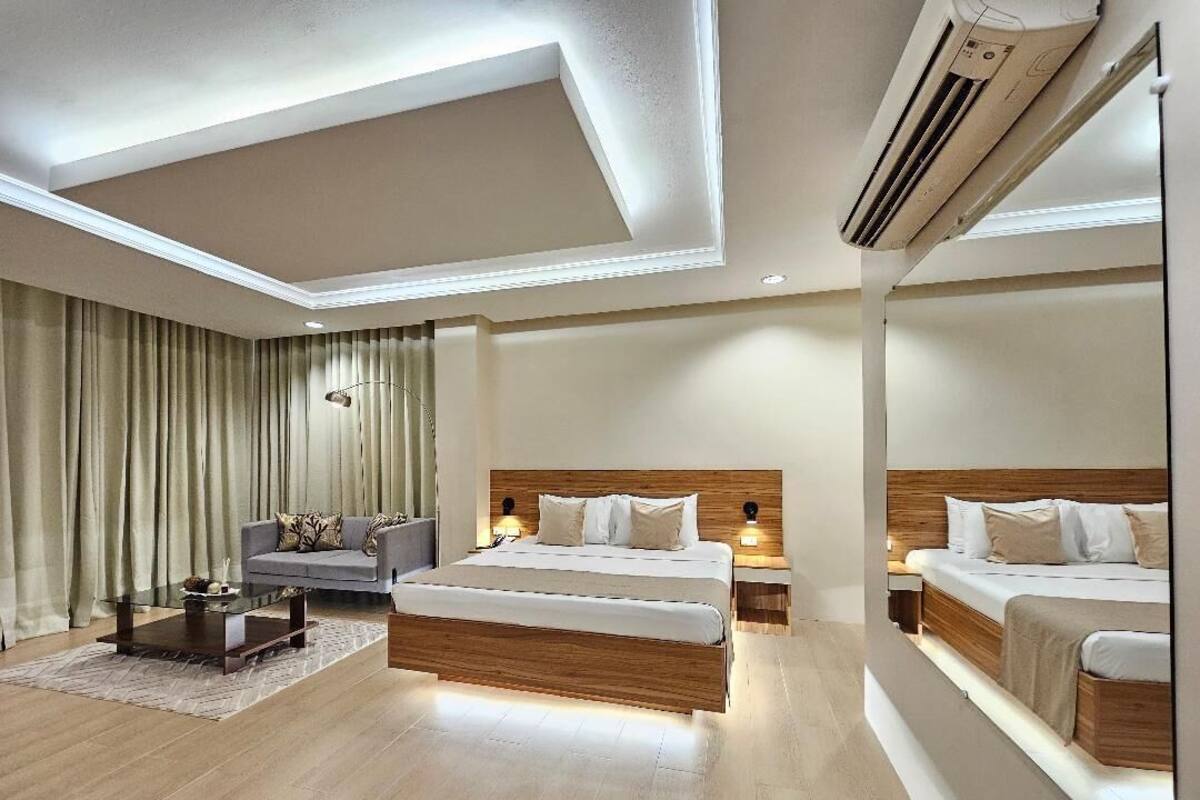Una habitación de hotel moderna con una cama grande, un sofá, una mesita de café y un espejo.
