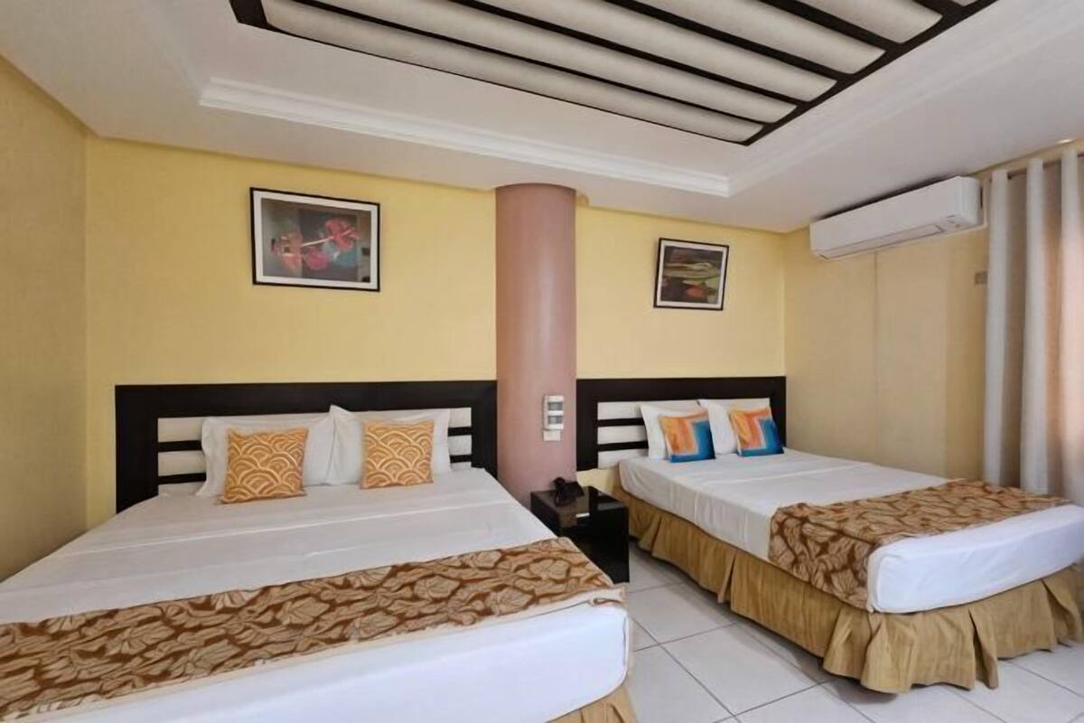 Habitación de hotel con dos camas, un pilar grande y obras de arte en las paredes.