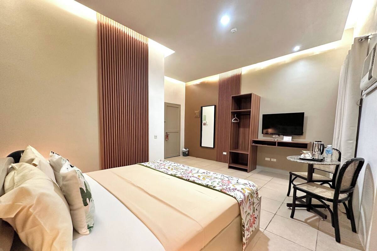 Habitación de hotel con cama, televisor, escritorio con silla y armario.