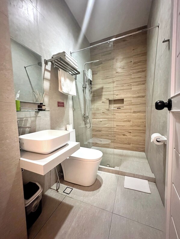 A modern bathroom with a glass-enclosed shower, a white sink, and a toilet.