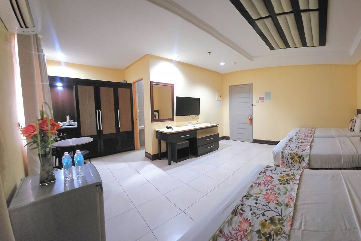 Habitación de hotel con cama, escritorio, silla, televisor y baño.
