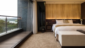 A modern hotel room with a large bed, a small bedside table, a nightstand, and a view of the outdoors.