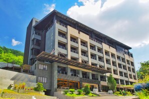 A multi-story hotel with a modern architectural design, featuring a prominent entrance with a covered walkway and landscaped gardens.