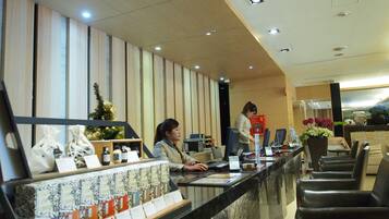 A hotel reception area with a counter, computer, and seating area.
