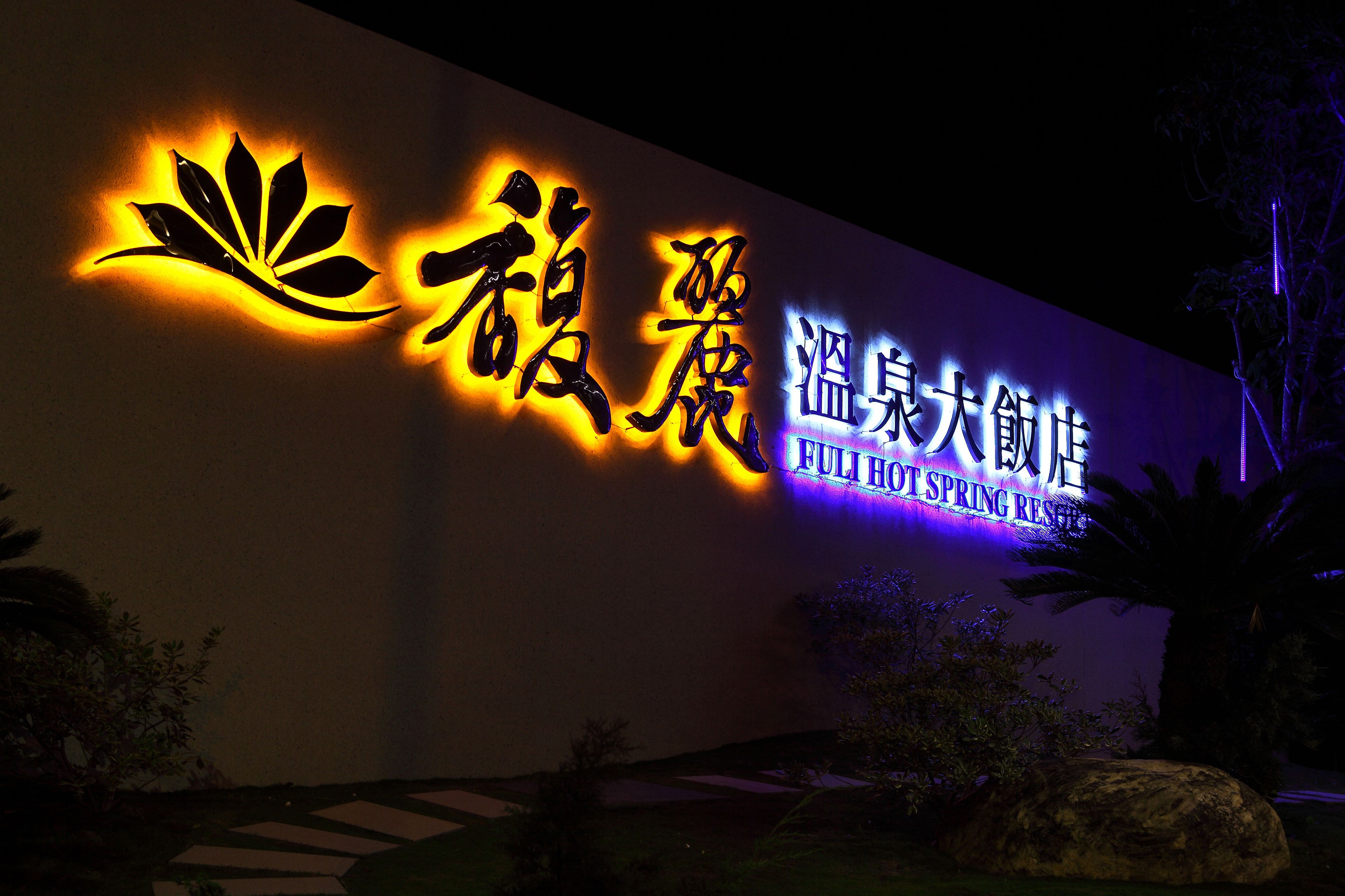 A hotel sign with illuminated Chinese characters and English text reading "Fuli Hot Spring Resort".