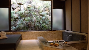 A spa room with a large window, a seating area, a reception desk, and a water feature.
