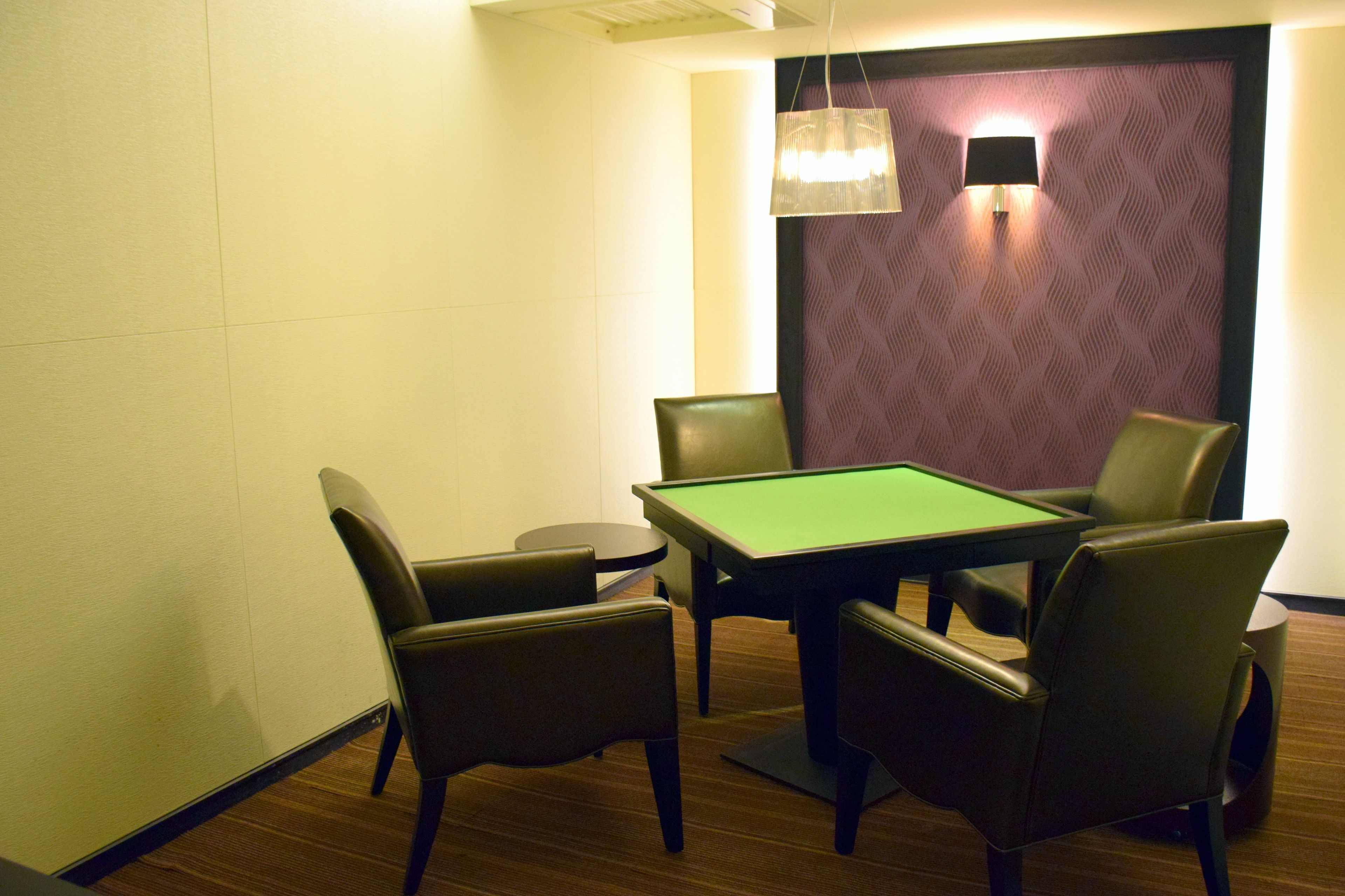 A room with a pool table, four chairs, a lamp, and a patterned wall.