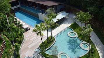 Una piscina al aire libre, sombrillas, sillones reclinables de piscina