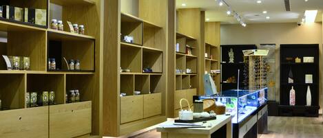 A wooden interior with shelves displaying various items, a table with a basket, and a display case with glassware.