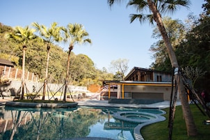 Una piscina al aire libre, sombrillas, sillones reclinables de piscina