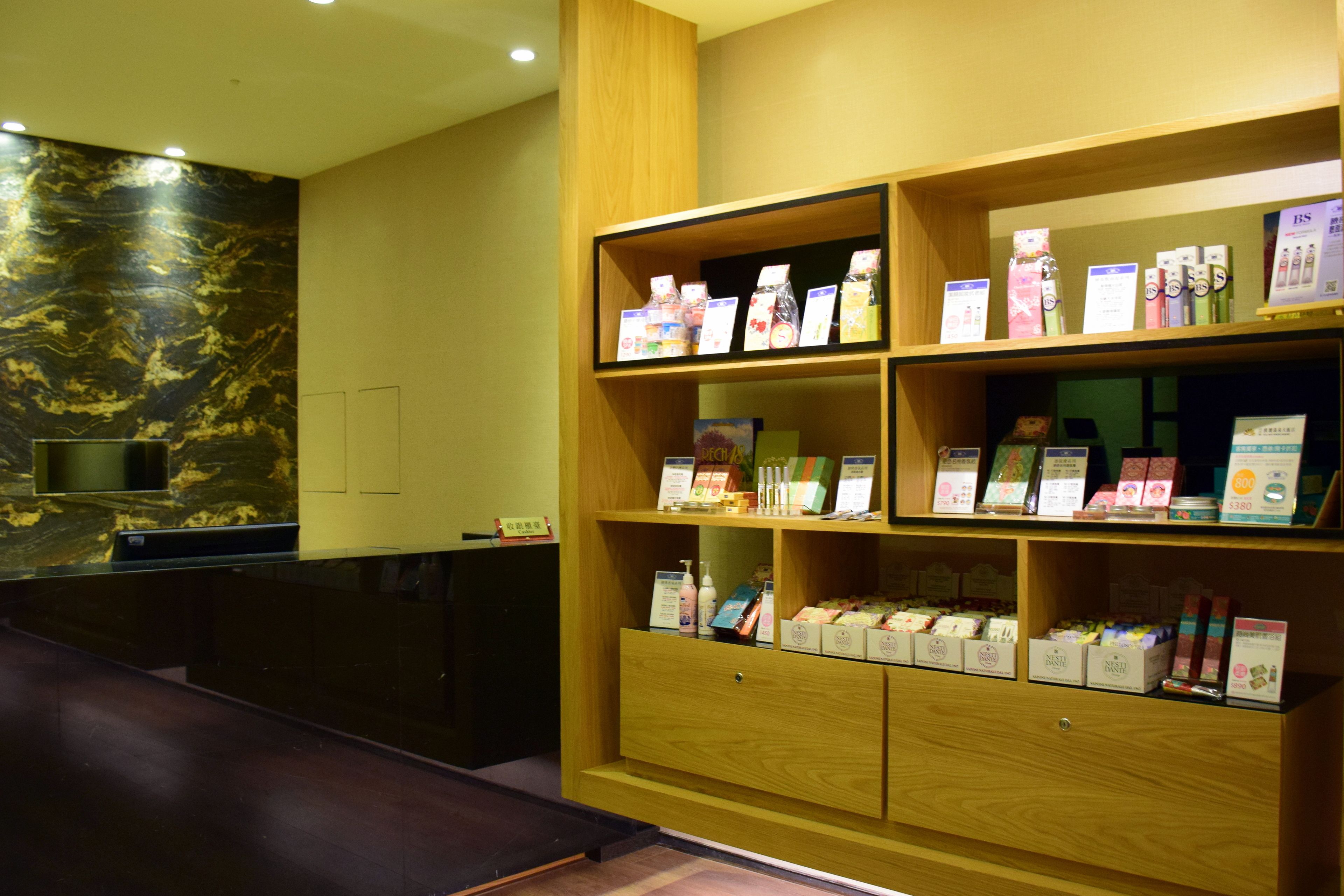 A reception area with a wooden reception desk, a marble wall, and shelves displaying various products.
