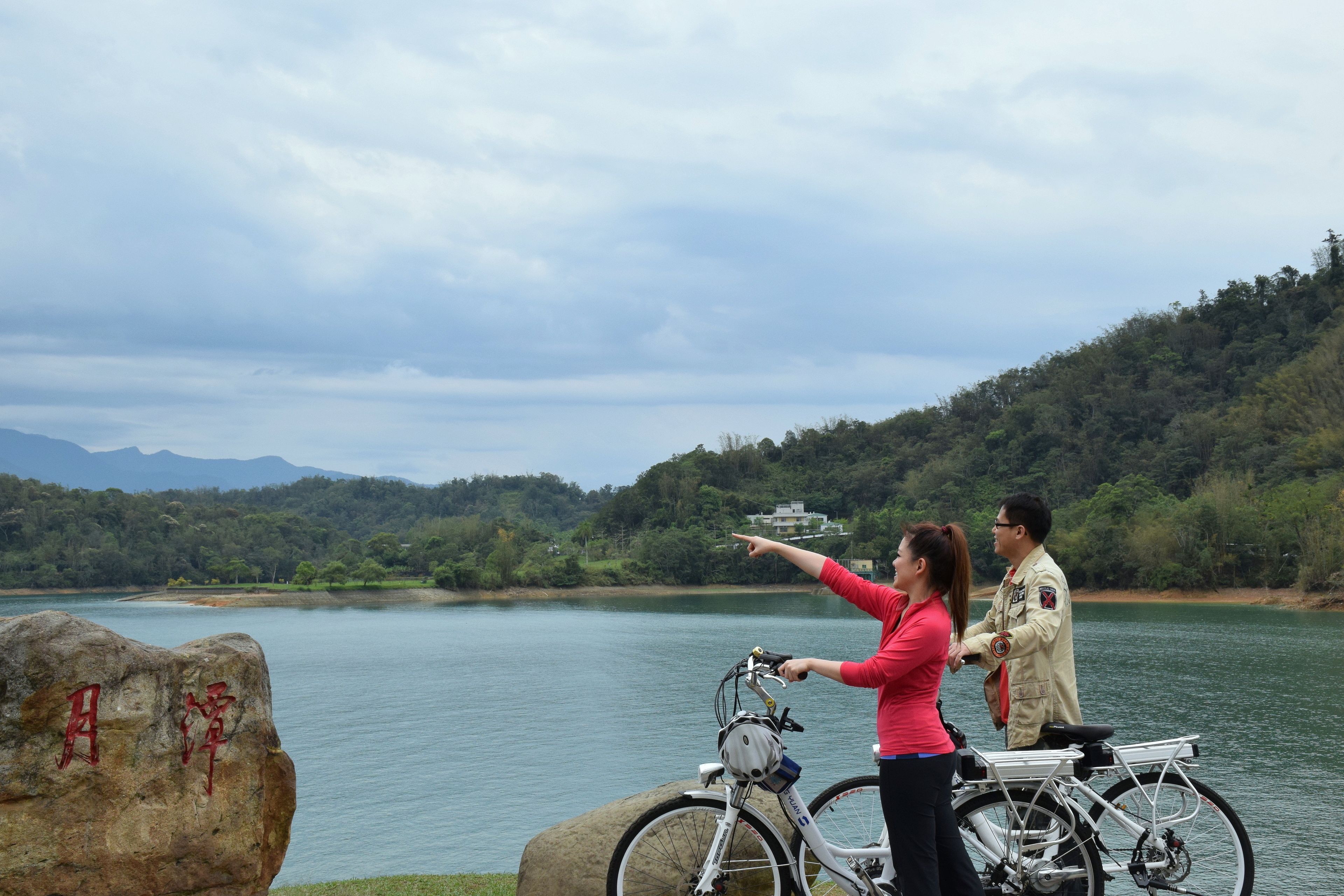 A couple standing by a lake with a mountain in the background.