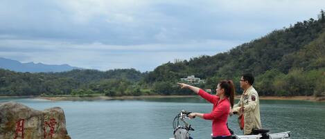 A couple standing by a lake with a mountain in the background.