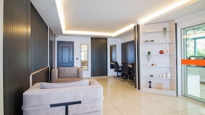 A modern living room with a sofa, a dining area, and a glass door leading outside. - Kas Maki Hotel (Kas)