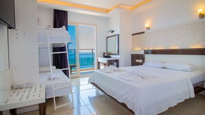 A hotel room with a bed, a desk, a mirror, and a view of the sea. - Kas Maki Hotel (Kas)