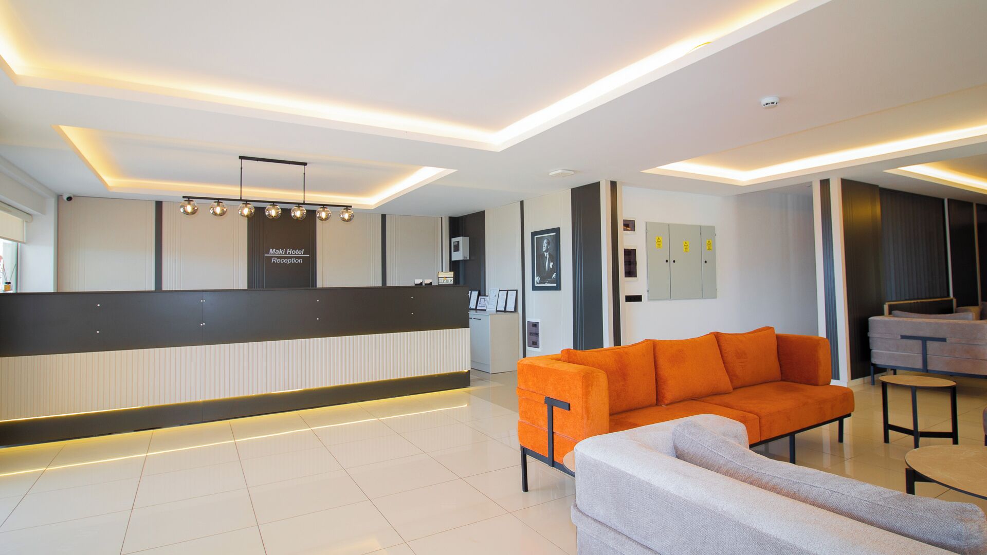 A hotel reception area with a modern design, featuring a reception desk, seating area with sofas, and a clean, tiled floor.