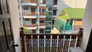 En balkon med et dekorativt gelænder, udsigt til en bygning med flere balkoner og et grønt tag.