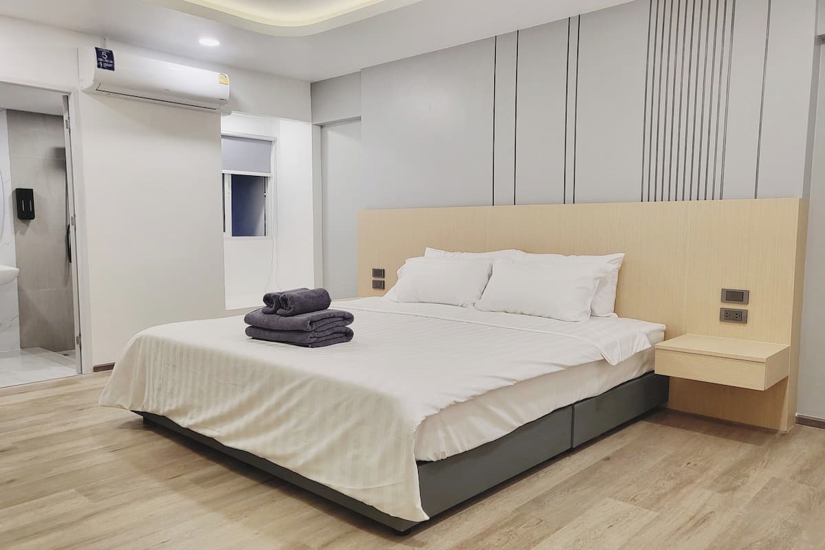 A modern bedroom with a large bed, bedside tables, and an air conditioning unit.