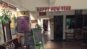 En restaurantindretning med et 'Happy New Year'-banner, en dørmåtte og en menutavle.