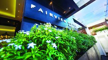 The exterior of the Fairview Hotel with a modern design, featuring a prominent sign and lush greenery in front.