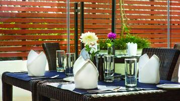 A dining table set with white napkins, clear glasses, and a white flower centerpiece.
