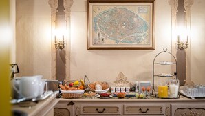 A breakfast buffet with various food items, a framed map on the wall, and a three-tiered stand with beverages. - Hotel Van Eyck (Bruges)