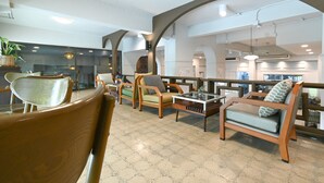 A spacious indoor area with wooden furniture, including chairs and a sofa, arranged around a central table.