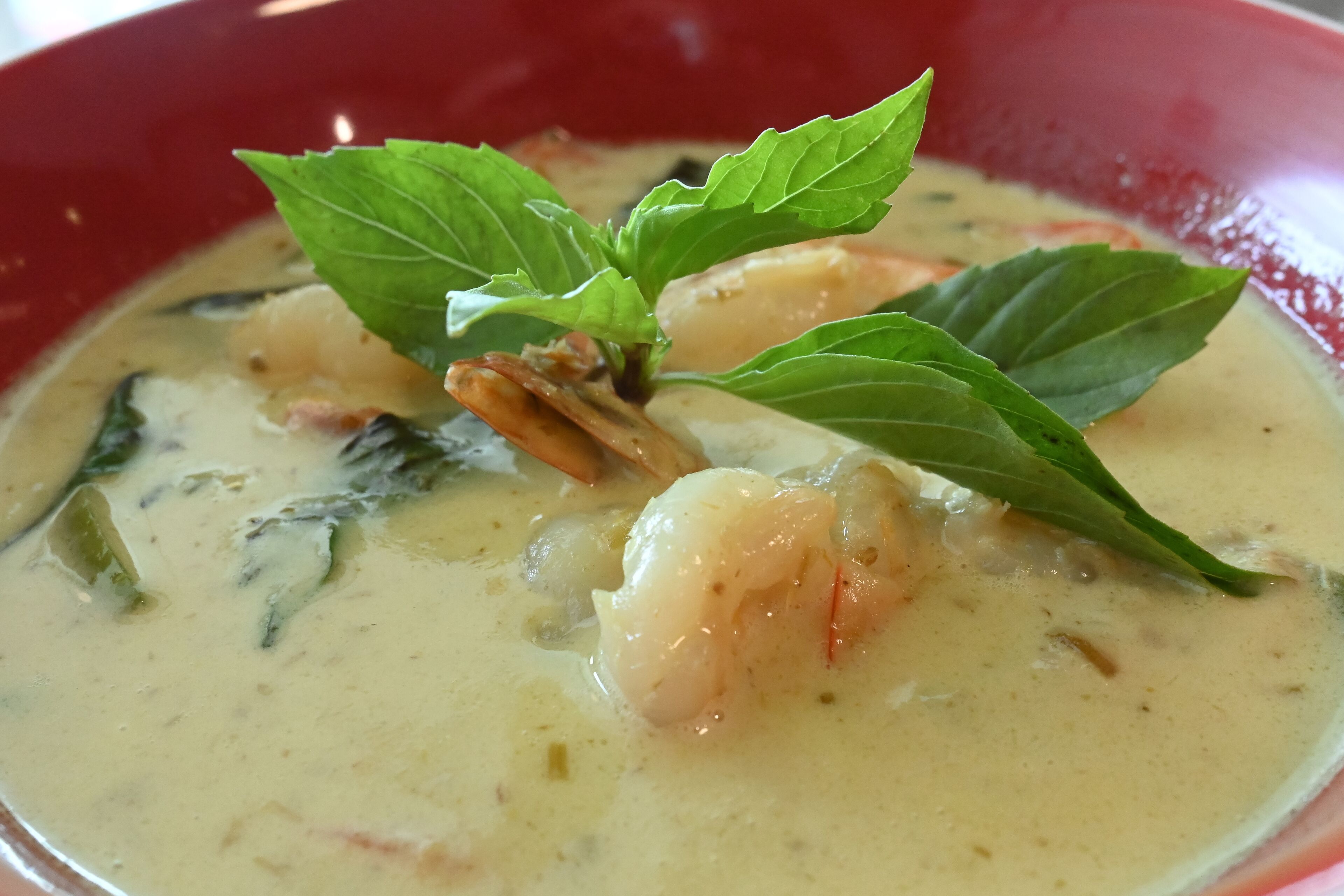 A bowl of creamy soup with shrimp and herbs.
