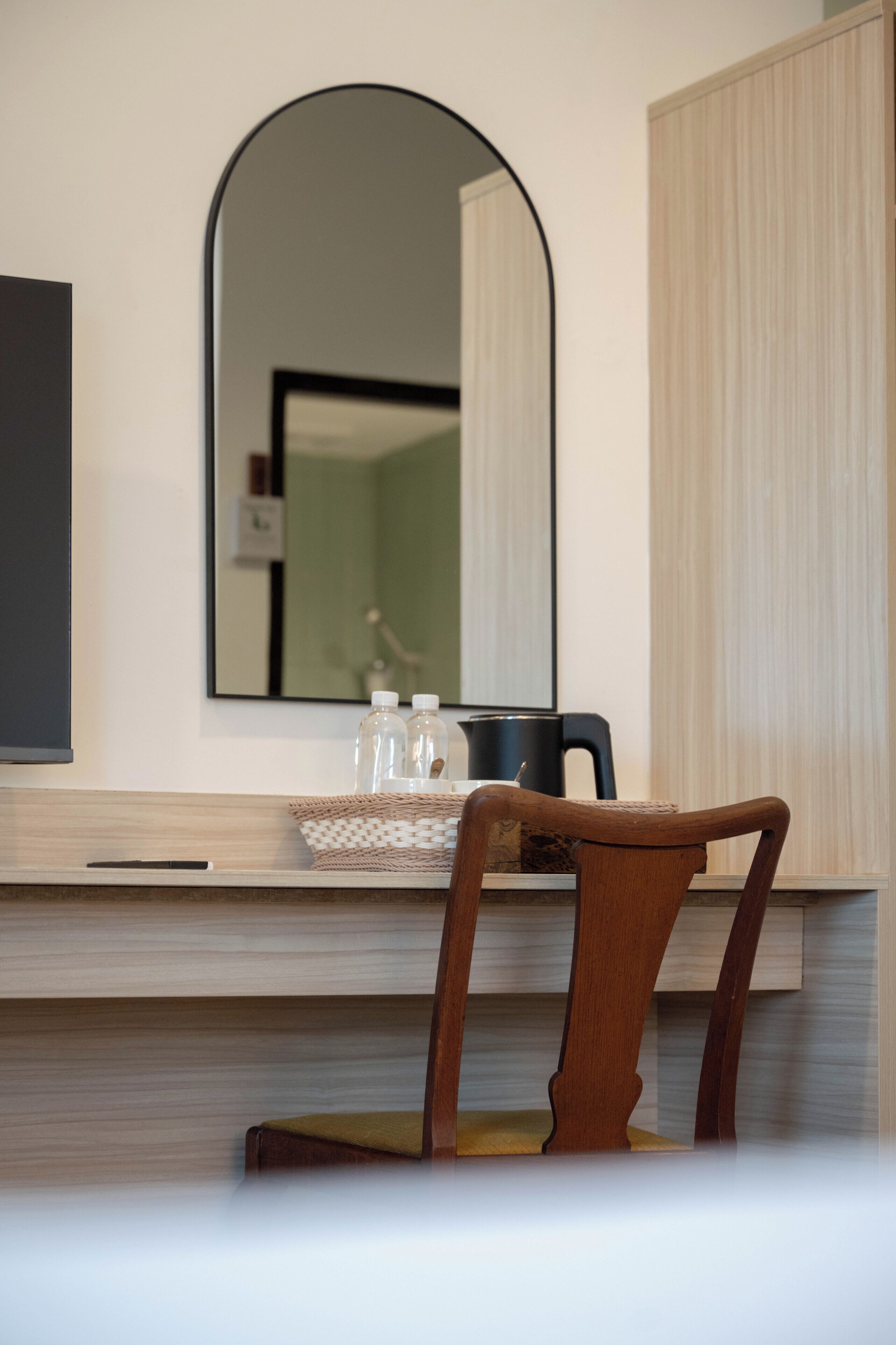 Una silla de madera frente a un mostrador con un espejo encima.