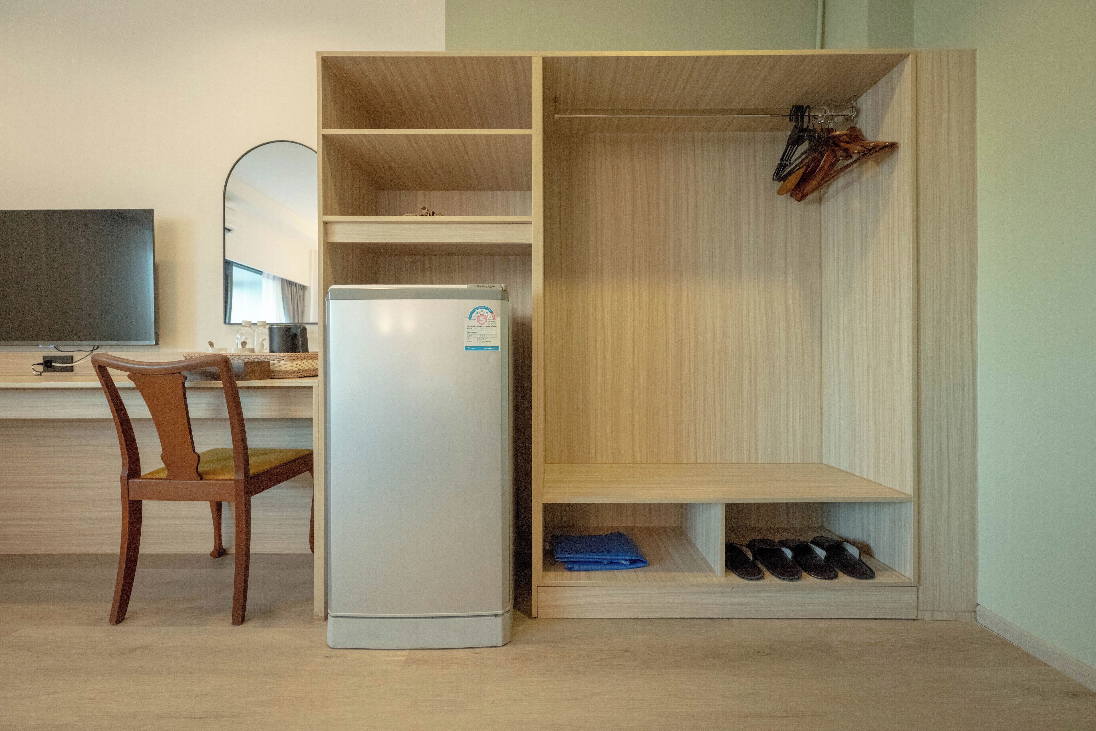 A compact kitchen with a refrigerator, wooden cabinets, and a chair.