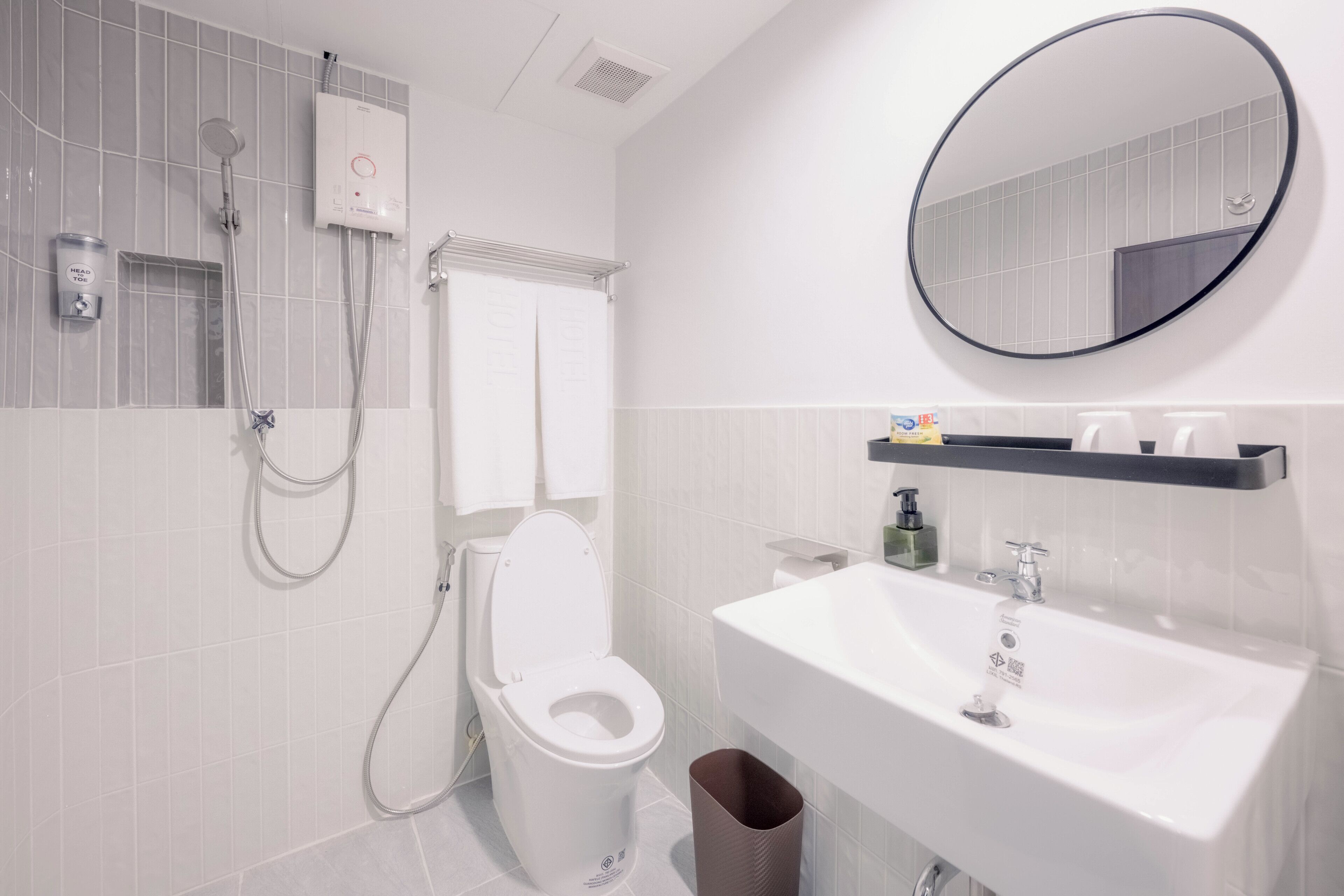 A modern bathroom with a toilet, shower, sink, and a mirror.
