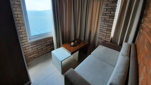 Una habitación acogedora con vista al mar, una mesa de madera con una bandeja y un sofá.