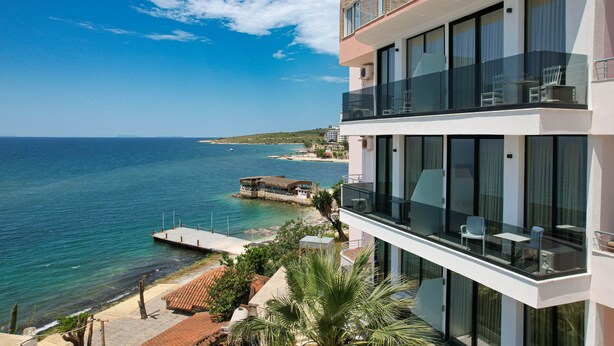 Un edificio moderno con un balcón con vistas a una playa y al mar.