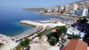 Zona costera con playa, sombrillas y muelle.