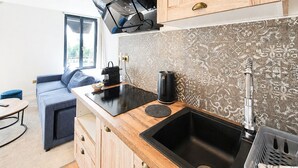 A modern kitchen with wooden cabinets, a black countertop, a sink, and a coffee machine. - HDG Appart's Hotel Gare de L'Isle Adam (Parmain)