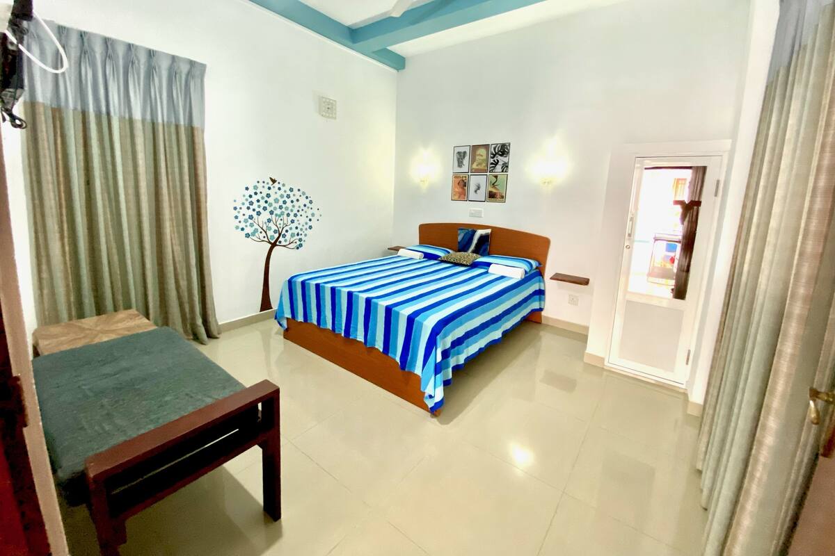 A bedroom with a bed, a bench, a ceiling fan, and a door.