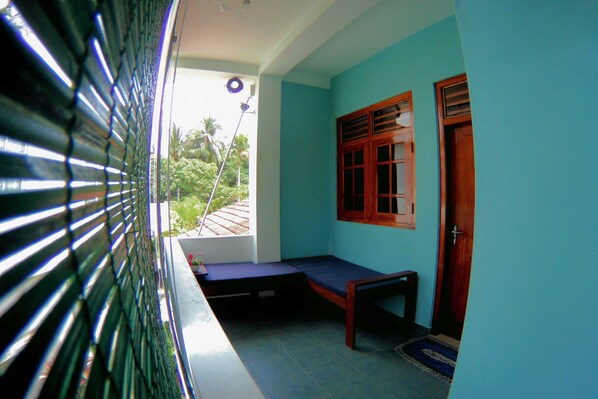 A room with a bed, a small table, a window with shutters, and a door. - Tamara Motels (Hikkaduwa)