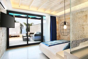 A modern bedroom with a bed, a TV, a glass door leading to a balcony, and a hanging light fixture. - Nur Beach Hotel (Kas)