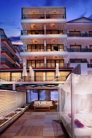 A multi-story hotel with balconies, outdoor seating, and a covered area with a bed. - Nur Beach Hotel (Kas)
