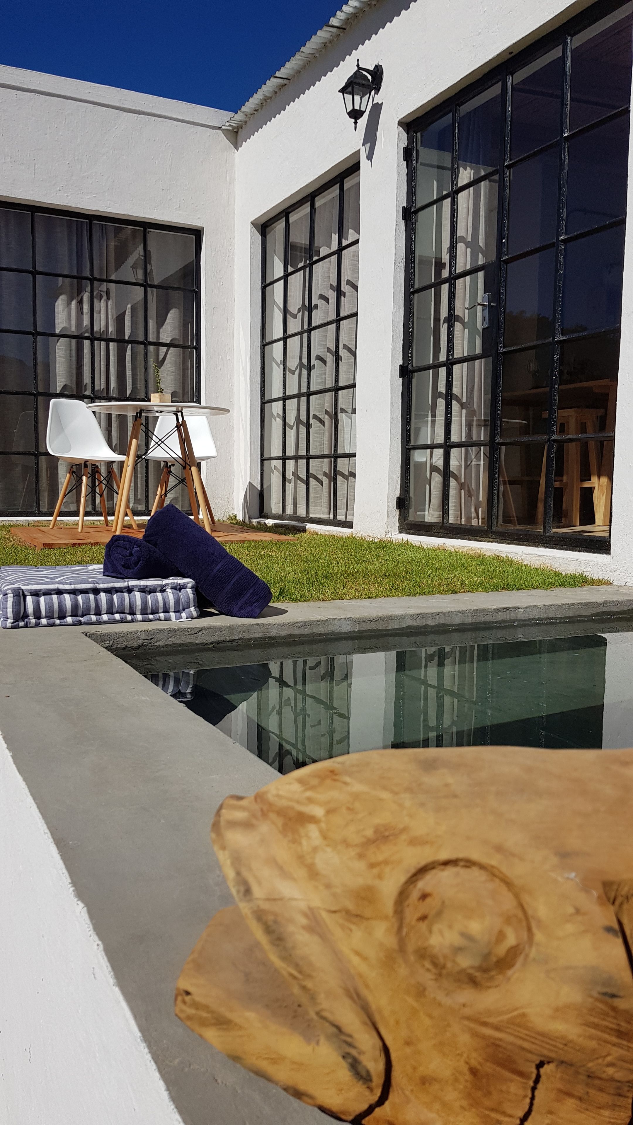 A modern house with large windows, a swimming pool, and outdoor furniture.