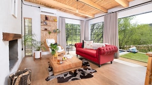 Een moderne woonkamer met een rode bank, een houten salontafel en een open haard.