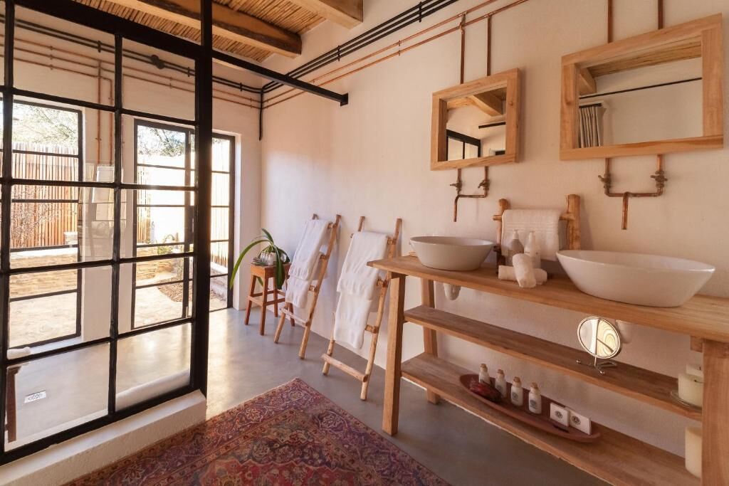Uma casa de banho moderna com prateleiras de madeira, um espelho grande e vista para o exterior.