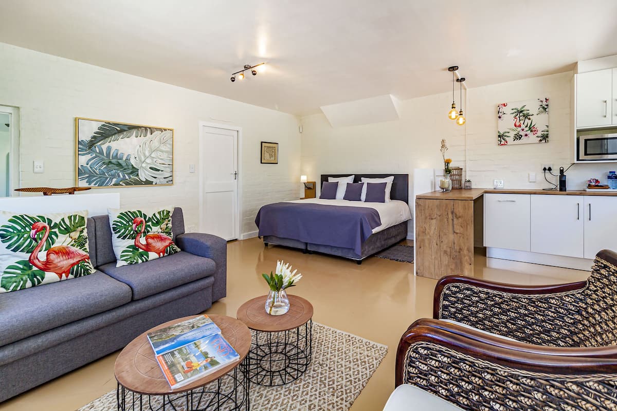 A compact living space with a sofa, a bed, a dining area, and a kitchenette.