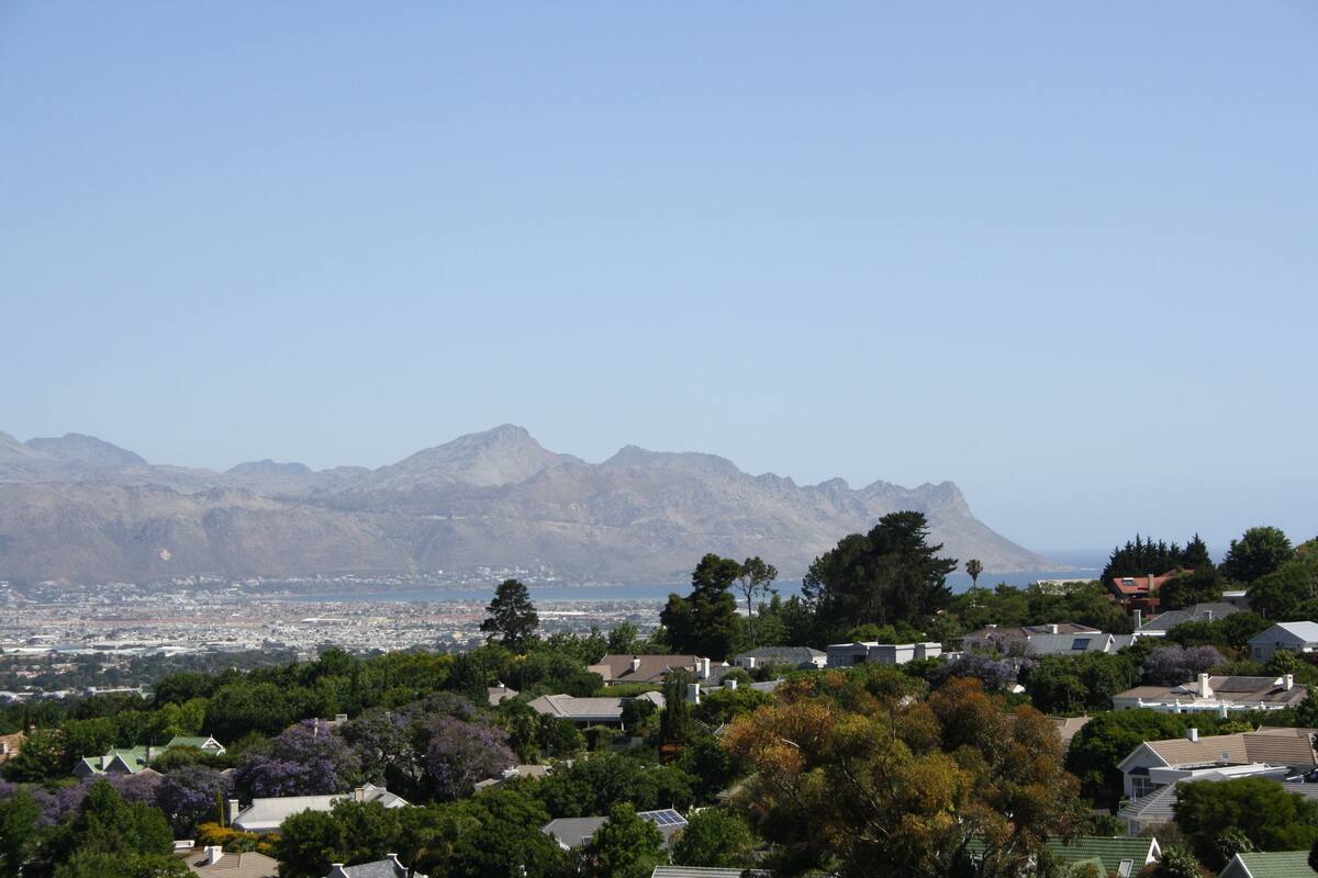 A residential area with houses, trees, and mountains in the background.