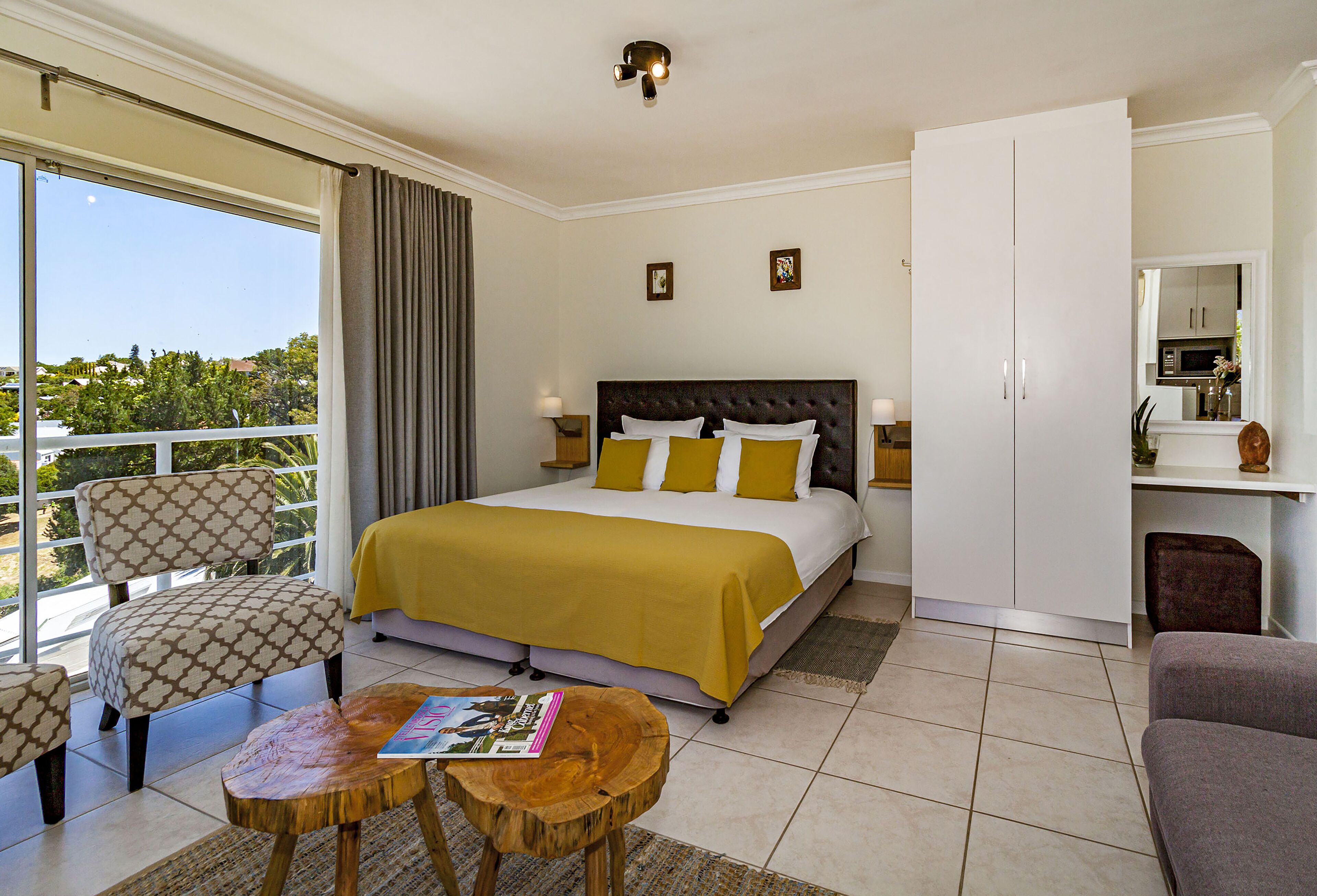 Habitación de hotel con cama, escritorio, silla y balcón con vistas.