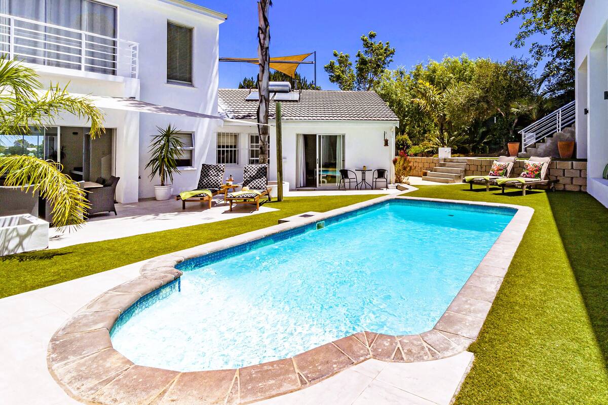 A modern house with a swimming pool, outdoor furniture, and a well-maintained lawn.