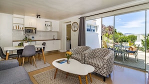 A compact living space with a kitchenette, a sofa, a dining area, and a balcony with a view. -  Morgen Guest House (Cape Town)