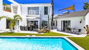 A modern house with a swimming pool, outdoor furniture, and a well-maintained lawn. -  Morgen Guest House (Cape Town)